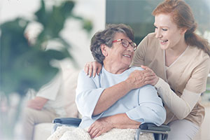 Old lady in wheelchair with carer happy knowing her care home uses an efficient care management solution