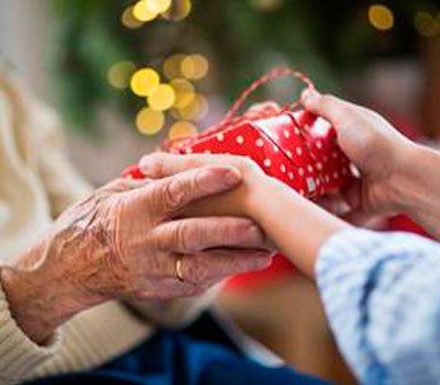 A child giving a woman living with dementia a christmas gift